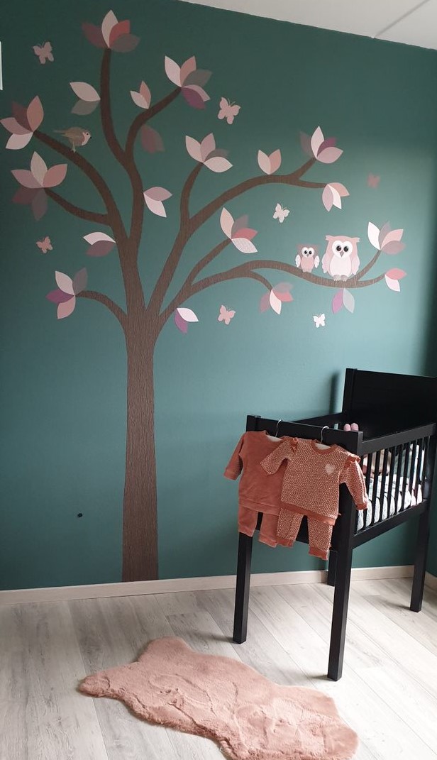droomboom op muur met daarnaast wiegje aankleed met oudroze vloerkleedje